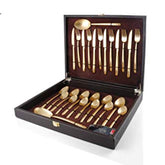 Elegant gold flatware set arranged in a black presentation box with velvet lining and clasp.